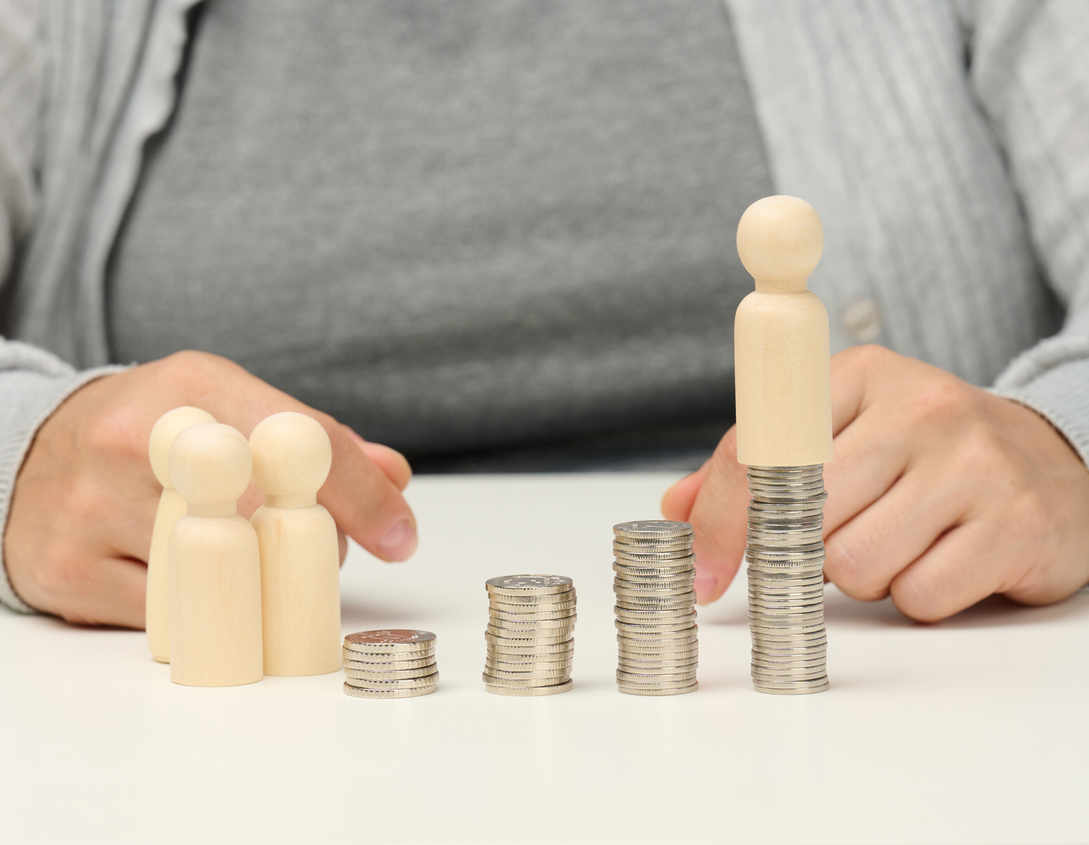 Representación gráfica de la pensión alimenticia con monedas y muñecos de madera