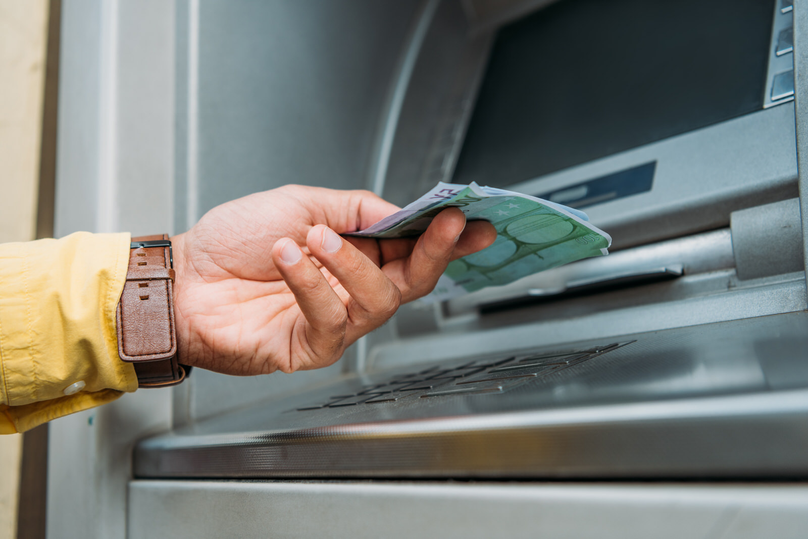Una mano recoge el dinero de un cajero automático de una reclamación realizada a su banco